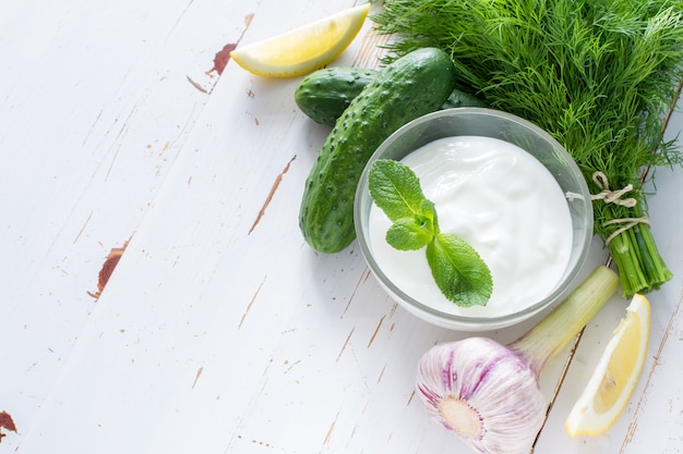 Tzatziki sauce ingredients, white wood background