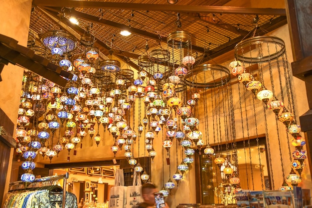 UAE Dubai lights Lanterns A man is standing under a chandelier that is hanging from a ceiling