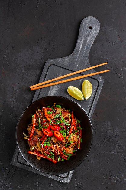 Udon noodles with pork and vegetables in sauce black plate no people