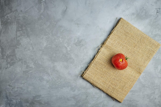 Ugly food. spoiled tomato on burlap on a gray concrete background. top view.