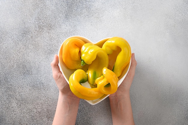 Ugly yellow pepper in white plate shaped of heart in child hands