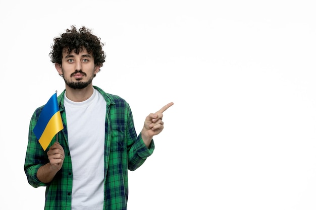 Ukraine russian conflict cute young brunette guy green shirt and ukrainian flag serous face