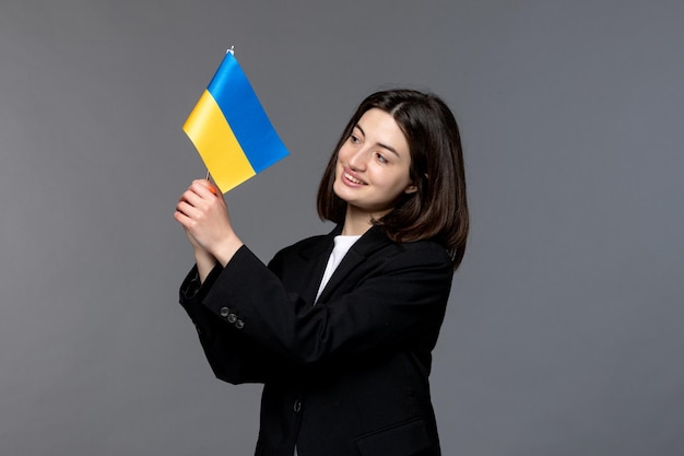 Ukraine russian conflict gorgeous young dark hair woman in black blazer looking at ukrainian flag