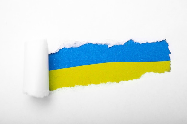 Ukrainian blue and yellow flag in the hole in paper