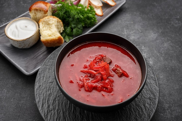 Ukrainian borscht with donuts sour cream lard and dill on a dark background