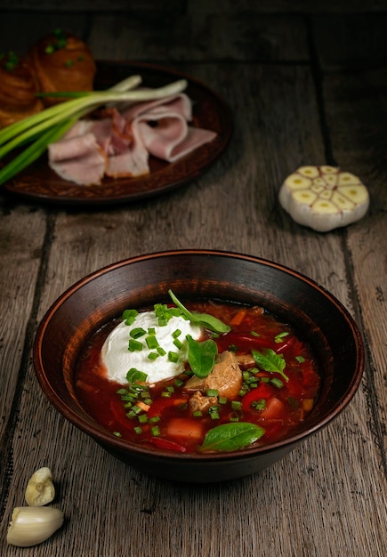 Ukrainian borscht on a wooden table with bacon and garlic