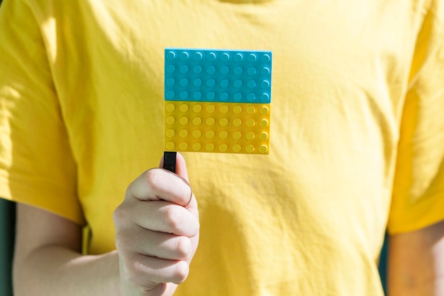 Ukrainian boy hold in hands ukrainian flag from blocks and hope to come back to home