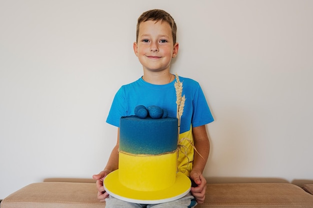 Ukrainian boy kid celebrating birthday holding big cake with flag of Ukraine