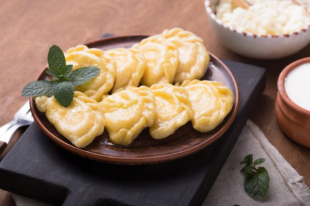 Ukrainian dumplings, pierogi or pyrohy, varenyky, vareniki, served with cottage cheese on board. National Russian cuisine, natural organic homemade bakery product, view from above.