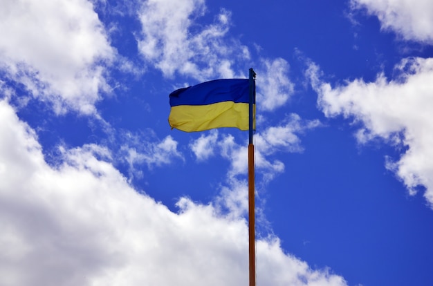 Ukrainian flag against the blue sky with clouds