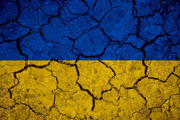 Ukrainian flag blue and yellow on a mud texture of dry cracks on the ground