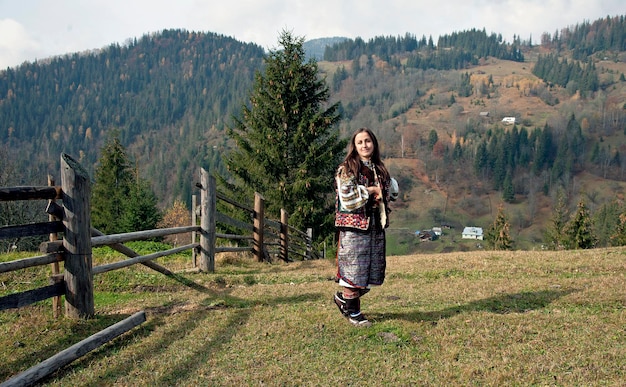 A Ukrainian girl in a Hutsul national costume stands against the background of a mountain landscape