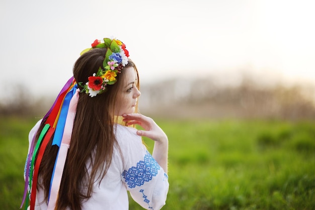 Ukrainian girl in a shirt and a flower wreath on his head on a background of green grass