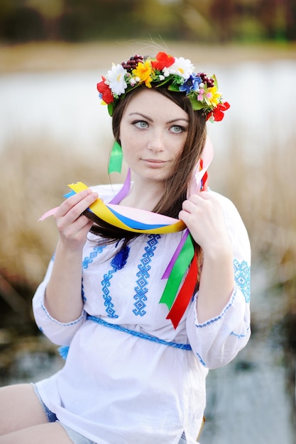 Ukrainian girl in a shirt and a flower wreath on his head on a background of the river