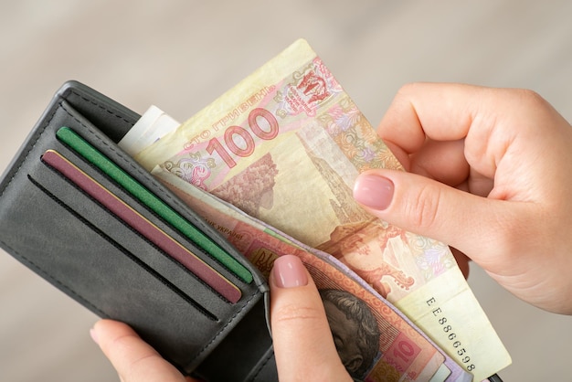 Ukrainian hryvnia various banknotes in grey wallet in female hands close up Money and finances in Ukraine paying for goods business and economy concept