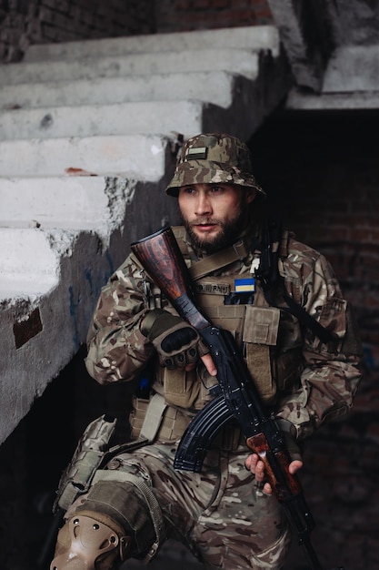 A Ukrainian military man poses against the background of destroyed buildings The war between Ukraine and Russia