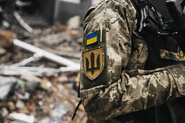 Ukrainian military woman with the Ukrainian flag in her hands on the background of an exploded house