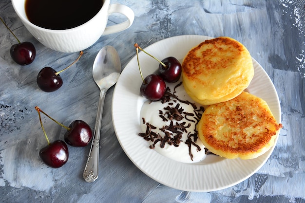 ukrainian syrniki with cherries on white plate isolated, close-up