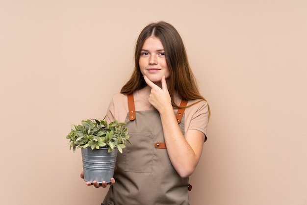 Ukrainian teenager gardener girl holding a plant laughing