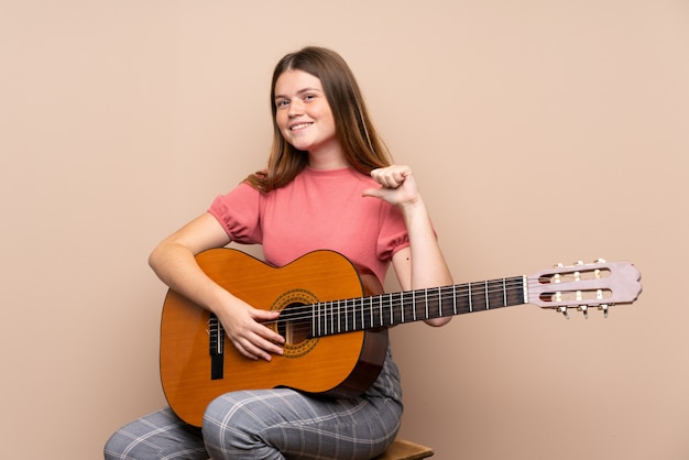 Ukrainian teenager girl with guitar over isolated  proud and self-satisfied