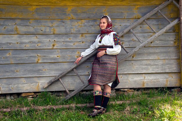 Photo ukrainian woman in an authentic hutsul costume stands near a ladder