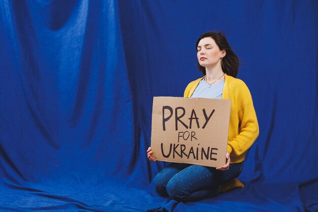 A Ukrainian woman in a yellow sweater and blue jeans with a stop the war sign Ukrainian girl suffered from the war No war