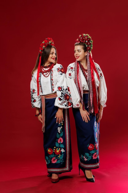 Ukrainian women in traditional ethnic clothing and floral red wreath on viva magenta studio background National embroidered dress call vyshyvanka Pray for Ukraine