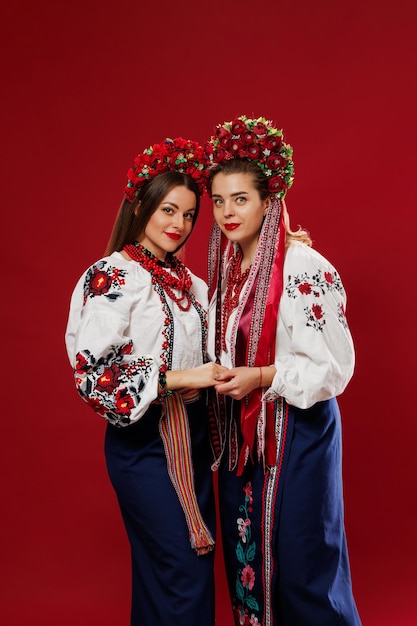 Ukrainian women in traditional ethnic clothing and floral red wreath on viva magenta studio background National embroidered dress call vyshyvanka Pray for Ukraine