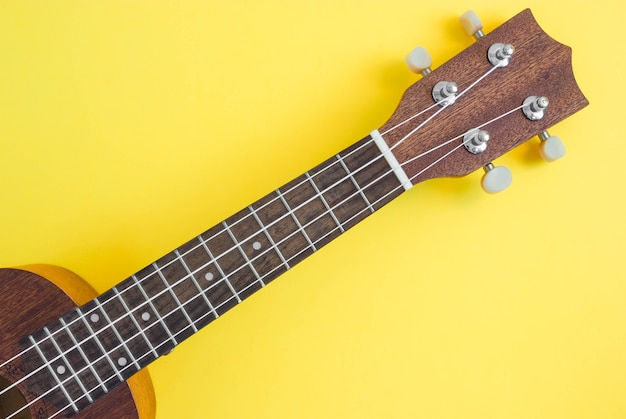 Ukulele on bright yellow background.