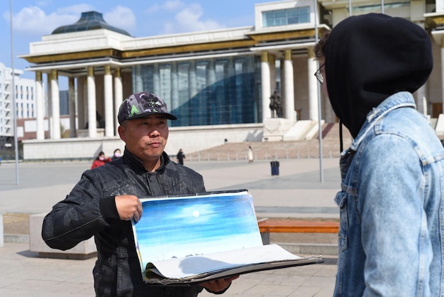 Ulaan Baatar Mongolia 05112022 Mongolian man shows souvenirs to a tourist for sale