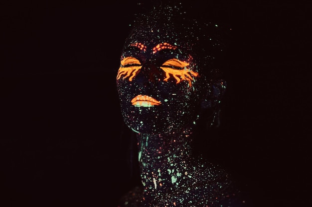 Ultraviolet make-up. Portrait of a girl painted in fluorescent powder. Halloween concept.