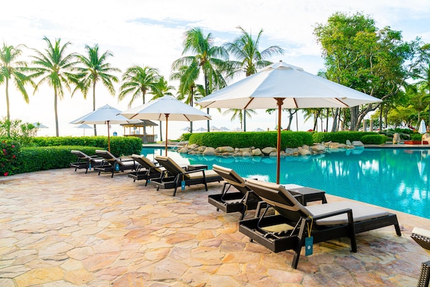 Umbrella and chair around swimming pool in resort hotel for leisure travel and vacation neary sea ocean beach