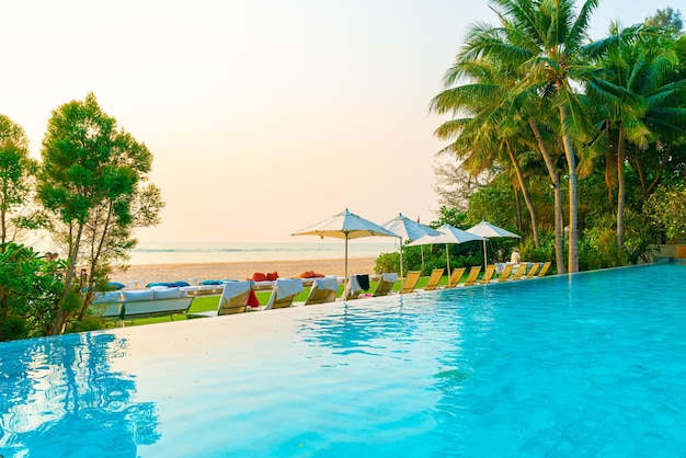 Umbrella and chair around swimming pool with sea ocean view for holiday vacation travel concept