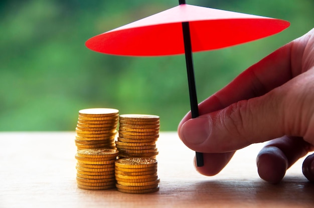 Umbrella covering gold coin with blurred nature background Security financial independence assurance and safety concept