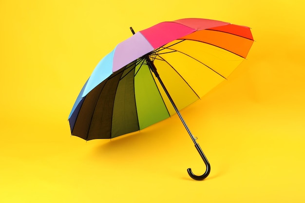 Umbrella of rainbow color on yellow background