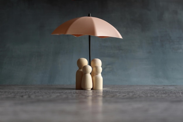 Umbrella and wooden dolls with copy space Family protection and insurance coverage concept