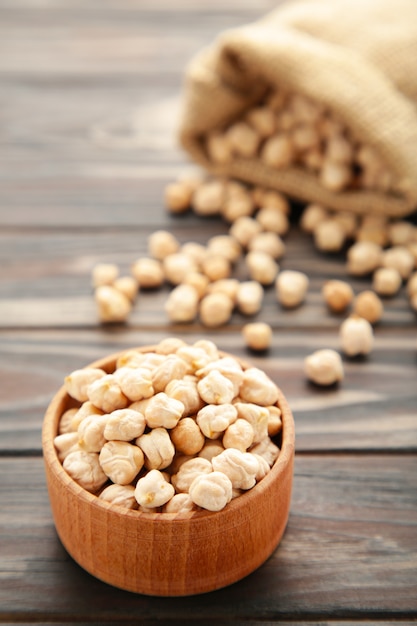 Uncooked chickpea in bag and bowl on brown wooden table