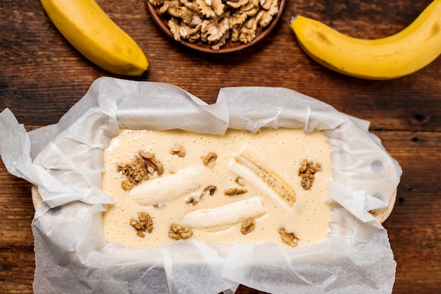 Uncooked dough banana bread in the form Cooking Wooden background View from above Sweet vegetarian food