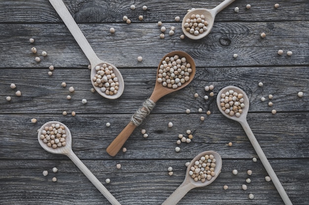 Uncooked dried legume chickpeas or garbanzo bean in various type of spoons on wooden table vegetaria...