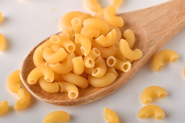 uncooked elbow macaroni on a white background