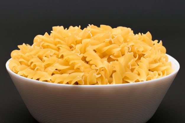 Uncooked Fusilli Pasta in White Bowl on Wooden Board