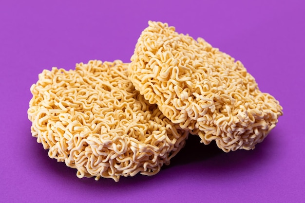 Uncooked instant noodles on violet background