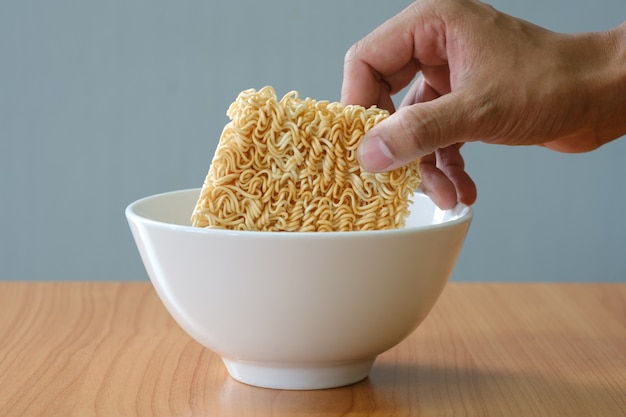 Uncooked Instant noodles and white bowl on wooden table