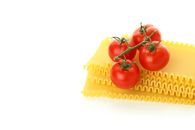 Uncooked lasagna and tomatoes isolated on white background