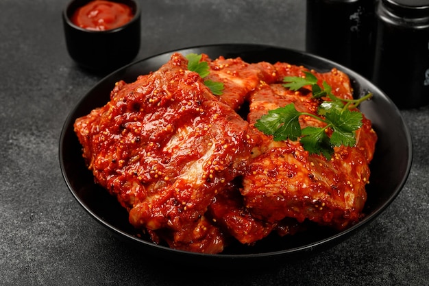 Uncooked Marinated pork bbq ribs for grill Raw ribs in marinade sauce on plate and dark background