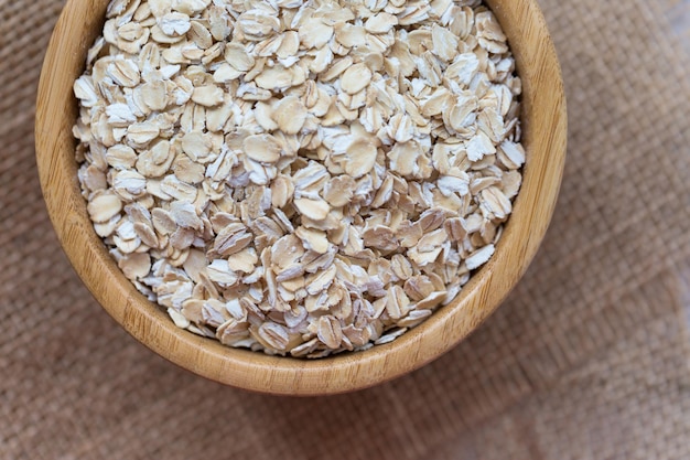 Uncooked oatmeal or oat flakes in a wooden bowl