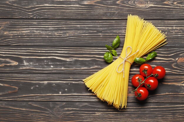 Uncooked  pasta, cherry tomatoes,  basil on a wooden background. top view. Place for text.