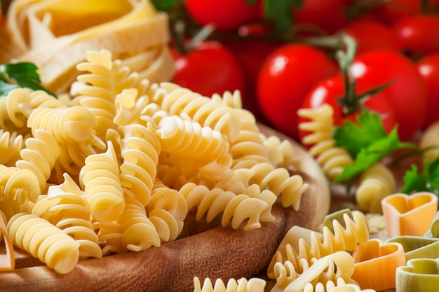 Uncooked pasta spiraline vegetables herbs and spices selective focus