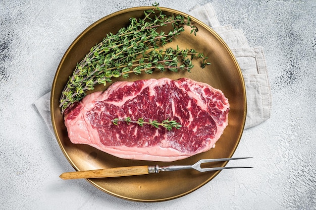 Uncooked Raw New York beef steak with thyme White background Top view