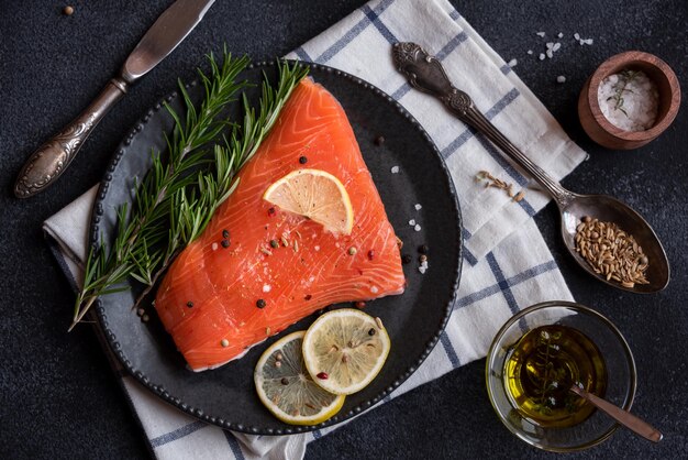 Uncooked raw salmon fish with herbs on dark background